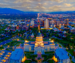 A breathtaking aerial view of Salt Lake City at twilight, with the Utah State Capitol building illuminated in the foreground and the cityscape stretching into the distance.