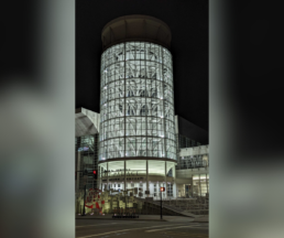 The illuminated Salt Palace Convention Center in Salt Lake City at night, featuring its iconic glass tower, where RootsTech attendees gather for the world's largest genealogy conference.
